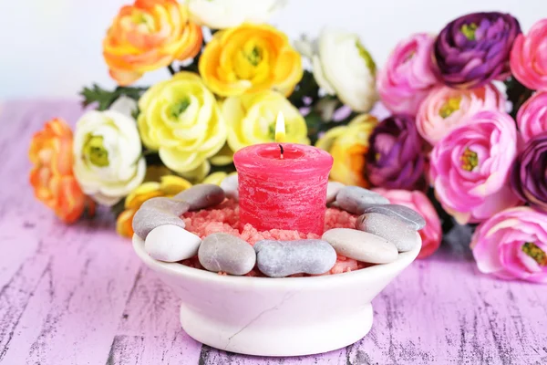 Komposition mit Wellness-Steinen, Kerze und Blumen auf farbigem Holztisch, auf hellem Hintergrund — Stockfoto