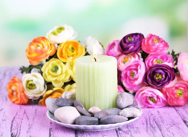 Spa 石块、 蜡烛和鲜花颜色木制的桌子，在明亮的背景上的组成 — 图库照片
