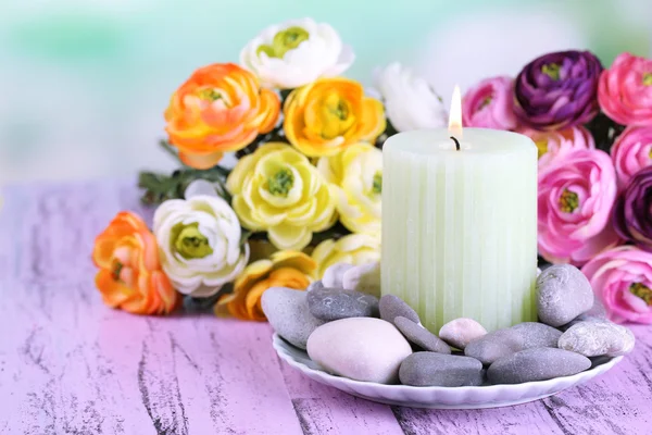 Compoziție cu pietre spa, lumânări și flori pe masă de lemn de culoare, pe fundal deschis — Fotografie, imagine de stoc