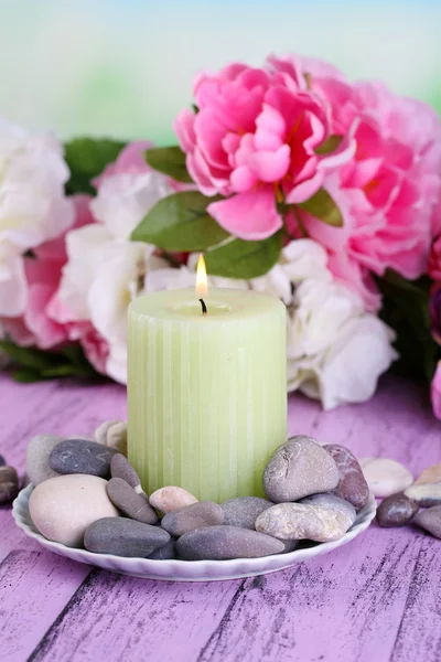 Composição com pedras de spa, vela e flores na mesa de madeira cor, no fundo claro — Fotografia de Stock