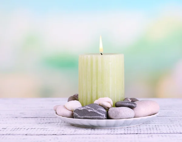 Složení s wellness kameny, svíčka na barevný dřevěný stůl, na světlé pozadí — Stock fotografie