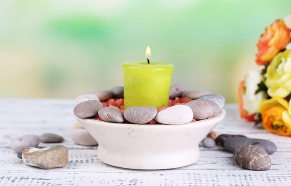 Composition avec pierres de spa, bougie et fleurs sur table en bois de couleur, sur fond clair — Photo