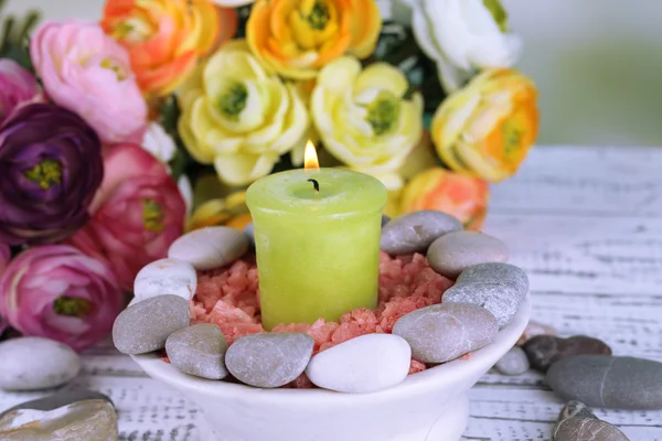 Composição com pedras de spa, vela e flores na mesa de madeira cor, no fundo claro — Fotografia de Stock