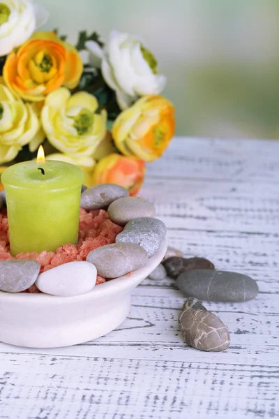 Composizione con pietre termali, candele e fiori su tavolo di legno a colori, su sfondo chiaro — Foto Stock