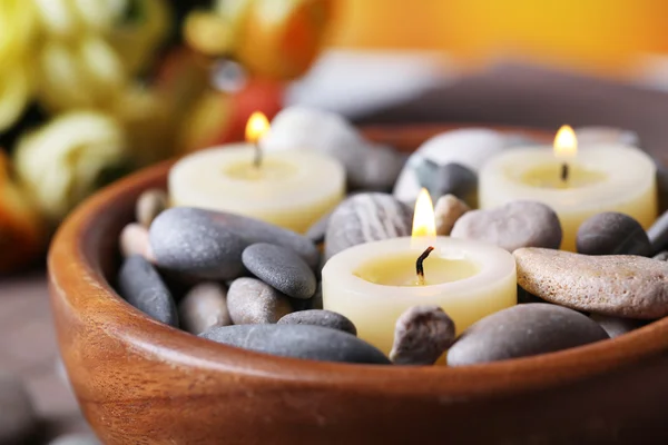 Composição com pedras de spa, velas e flores no tapete de bambu, no fundo brilhante — Fotografia de Stock