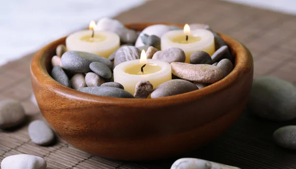 Samenstelling met spa stenen, kaarsen op bamboe mat achtergrond — Stockfoto