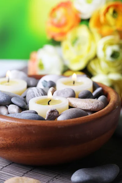 Composition with spa stones, candles  and flowers on  bamboo mat, on  bright background — Stock Photo, Image