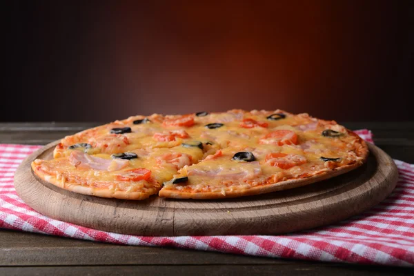 Smakelijke pizza op tafel op donkere rode achtergrond — Stockfoto