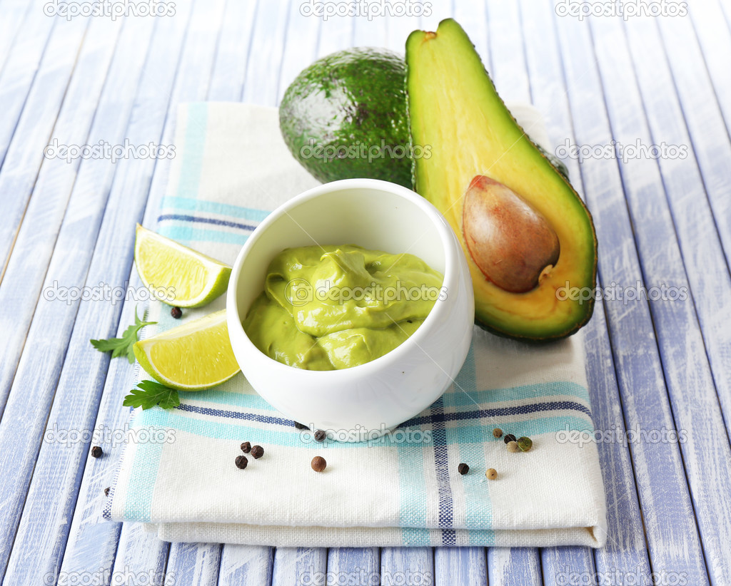 Fresh guacamole in bowl on wooden table