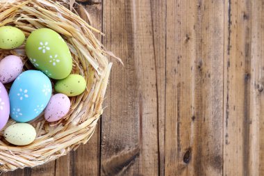 Yuvadaki Paskalya yumurtaları renkli ahşap arka planda