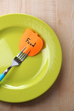 Not kağıdı çatalı tabağa renk ahşap arka plan üzerinde ekli mesajla