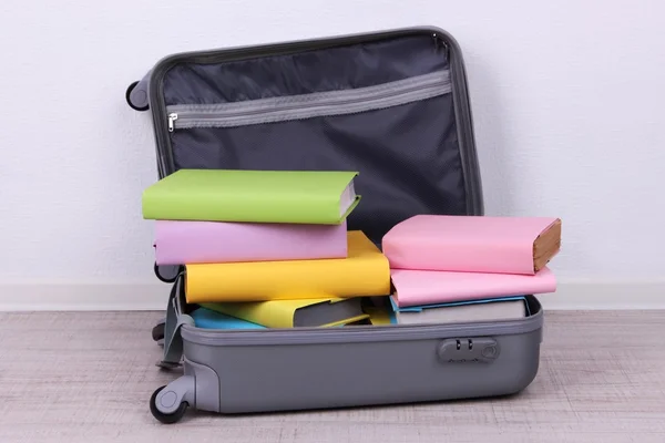 Books in suitcase on wall background — Stock Photo, Image