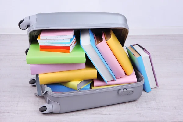 Books in suitcase on wall background — Stock Photo, Image