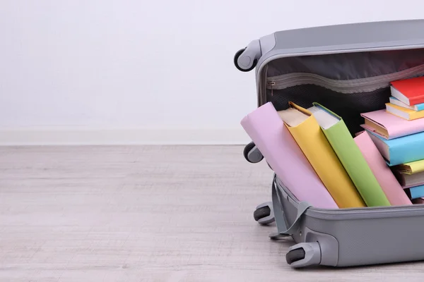 Books in suitcase on wall background — Stock Photo, Image