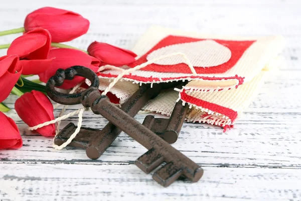 Key to love and happiness. Composition with key, decorative bag and flowers. Conceptual photo. On color wooden background — Stock Photo, Image