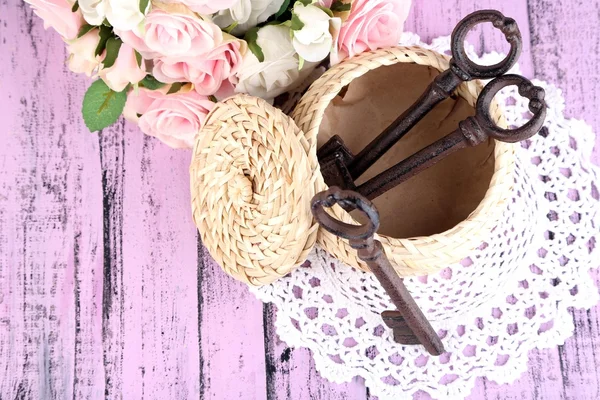 Key to success and happiness. Composition with keys in wicker basket and flowers. Conceptual photo. On color wooden table, on light background — Stock Photo, Image