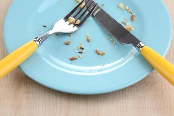 Plate with crumbs on wooden background — Stock Photo, Image