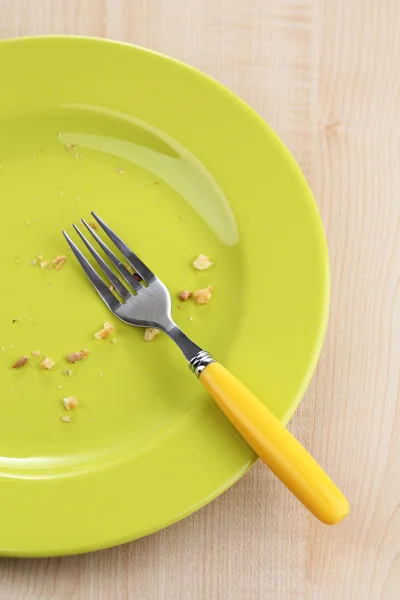 Plate with crumbs and used fork on wooden background — Stock Photo, Image