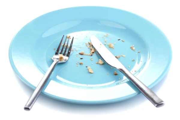 Plate with crumbs and used fork and knife, close-up, on white background — Stock Photo, Image