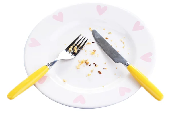 Plate with crumbs and used fork and knife, close-up, on white background — Stock Photo, Image