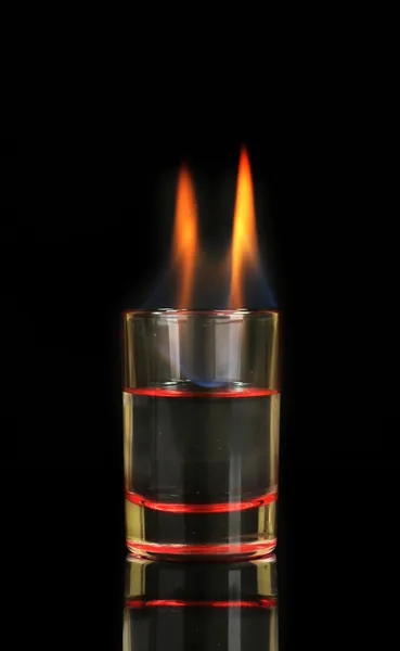 Vidro com álcool em chamas no fundo preto — Fotografia de Stock