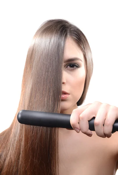 Женщина делает прическу с выпрямителем волос изолирован на белом — стоковое фото