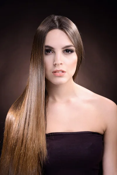 Beautiful young woman with long hair on dark brown background — Stock Photo, Image