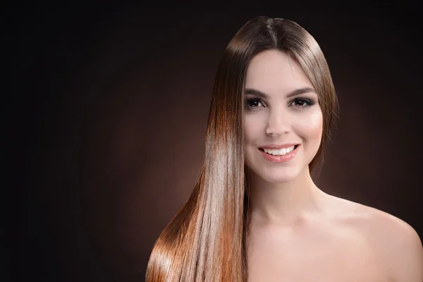 Beautiful young woman with long hair on dark brown background — Stock Photo, Image