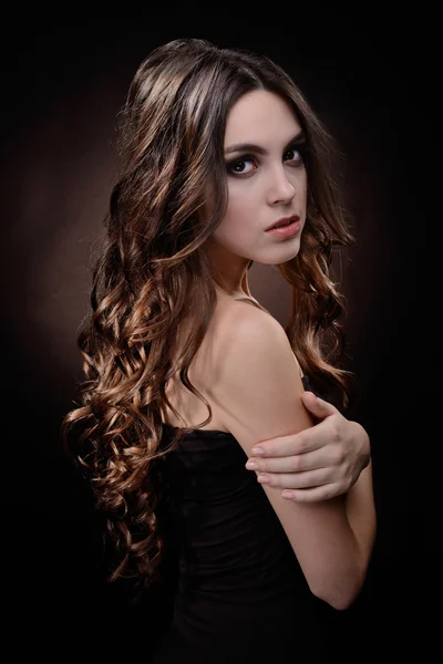 Beautiful young woman with long hair on dark brown background — Stock Photo, Image