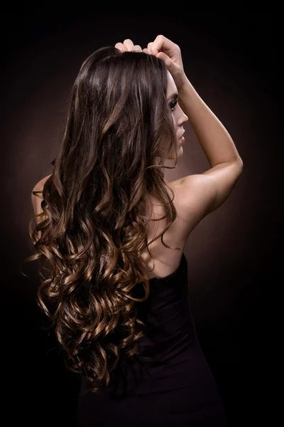 Hermosa joven con el pelo largo sobre fondo marrón oscuro — Foto de Stock