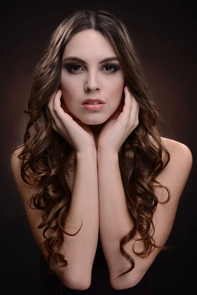 Piękna młoda kobieta z długimi włosami na ciemnym tle brązowy — Zdjęcie stockowe