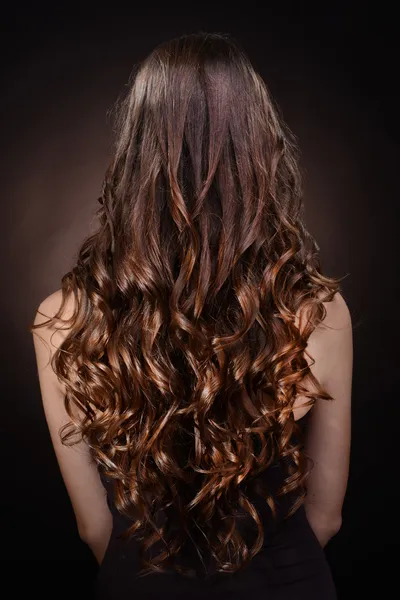 Bella giovane donna con i capelli lunghi su sfondo marrone scuro — Foto Stock