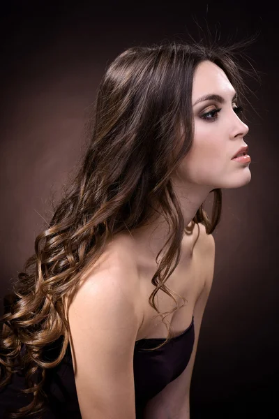 Όμορφη νεαρή γυναίκα με μακριά μαλλιά σε σκούρο καφέ φόντο — Φωτογραφία Αρχείου