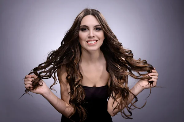 灰色の背景上の長い髪と美しい若い女性 — ストック写真