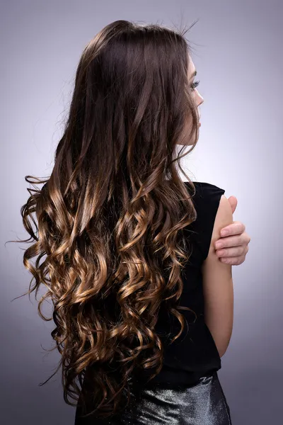 Schöne junge Frau mit langen Haaren auf grauem Hintergrund — Stockfoto