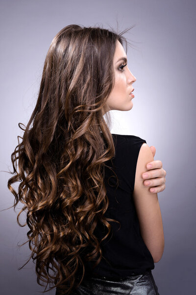 Красивая молодая женщина с длинными волосами на сером фоне

