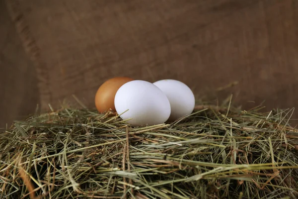 Eieren op hooi op jute achtergrond — Stockfoto