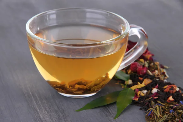 Tazza di tè con tè aromatico secco su sfondo di legno — Foto Stock