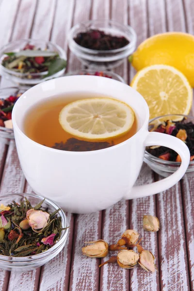 Tasse de thé avec thé sec aromatique dans des bols sur fond en bois — Photo