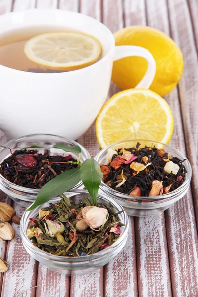 Taza de té con té seco aromático en cuencos sobre fondo de madera — Foto de Stock