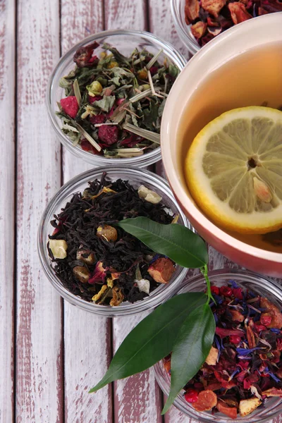 Kopp te med aromatiska torr te i skålar på trä bakgrund — Stockfoto