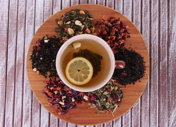 Xícara de chá com chá seco aromático em stand no fundo de madeira — Fotografia de Stock