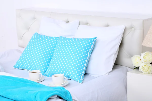 Cups of coffee on comfortable soft bed with pillows — Stock Photo, Image