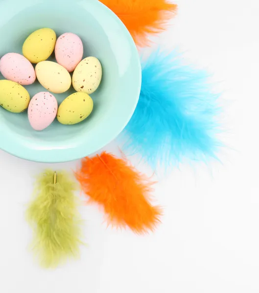Huevos de Pascua en tazón y plumas decorativas aisladas en blanco — Foto de Stock
