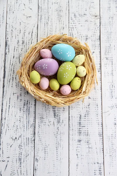 Пасхальні яйця в гнізді на кольоровому дерев'яному фоні — стокове фото