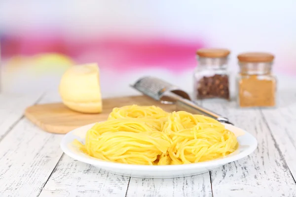 Composition with tasty spaghetti, grater, cheese, and spices on wooden table, on light background — Stock Photo, Image