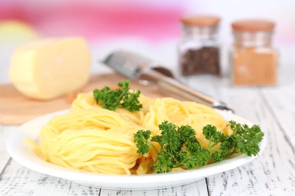 Composition with tasty spaghetti, grater, cheese, and spices on wooden table, on light background — Stock Photo, Image