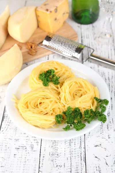 Composition with tasty spaghetti, grater, cheese, on wooden table background — Stock Photo, Image