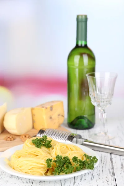 Composição com espaguete saboroso, ralador, queijo, garrafa de vinho e vidro na mesa de madeira, no fundo claro — Fotografia de Stock