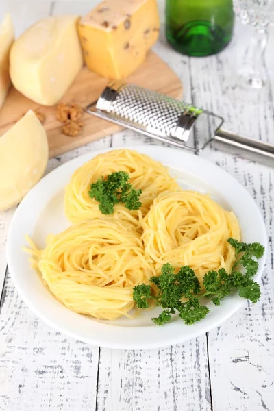 Composition with tasty spaghetti, grater, cheese, on wooden table background — Stock Photo, Image